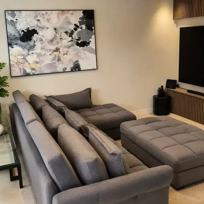 Sofá de canto cinza com chaise e puff, na sala de TV